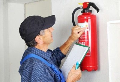 A service professional inspecting a fire extinguisher